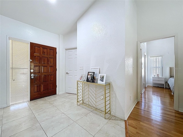 1599 Mcauliffe Ln, Palm Harbor, FL 34683 - entryway featuring baseboards, lofted ceiling, light wood-style floors, and a textured wall