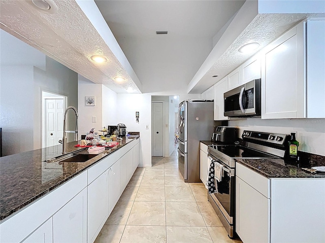 1599 Mcauliffe Ln, Palm Harbor, FL 34683 - kitchen with appliances with stainless steel finishes, a sink, white cabinets, and dark stone counters