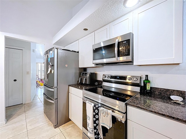 1599 Mcauliffe Ln, Palm Harbor, FL 34683 - kitchen with stainless steel appliances, light tile patterned floors, white cabinetry, and dark stone counters