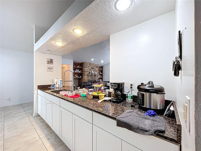 1599 Mcauliffe Ln, Palm Harbor, FL 34683 - kitchen with light tile patterned flooring, dark stone countertops, white cabinets, a sink, and a textured ceiling