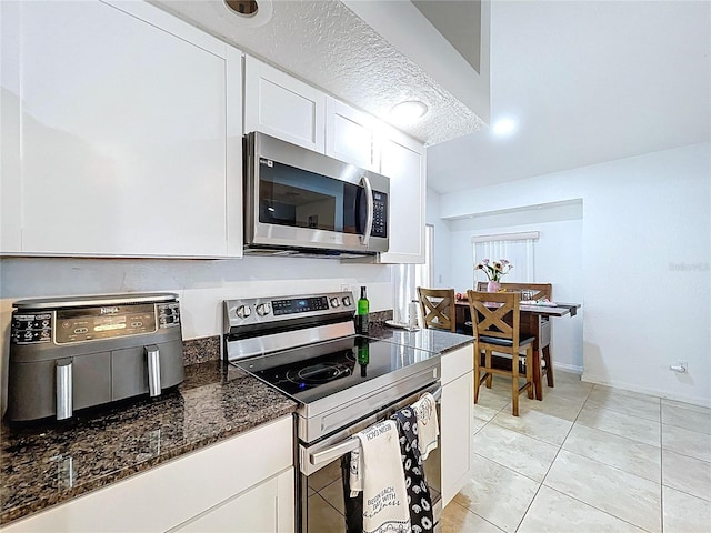 1599 Mcauliffe Ln, Palm Harbor, FL 34683 - kitchen featuring stainless steel appliances, white cabinetry, dark stone countertops, and light tile patterned floors
