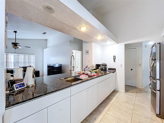 1599 Mcauliffe Ln, Palm Harbor, FL 34683 - kitchen featuring freestanding refrigerator, a sink, white cabinets, ceiling fan, and dark stone counters