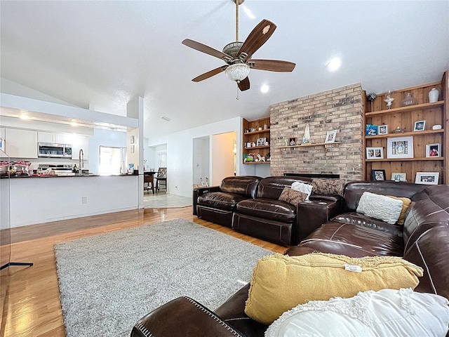 1599 Mcauliffe Ln, Palm Harbor, FL 34683 - living room with a ceiling fan, wood finished floors, vaulted ceiling, and a fireplace