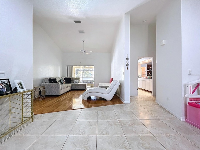 1599 Mcauliffe Ln, Palm Harbor, FL 34683 - living room with high vaulted ceiling, a ceiling fan, light tile patterned flooring, and baseboards
