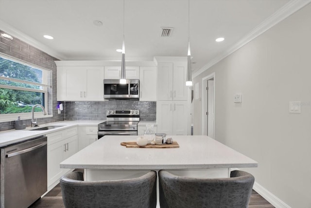6020 N 50th St, Tampa, FL 33610 - kitchen featuring stainless steel appliances, a sink, a kitchen island, ornamental molding, and backsplash