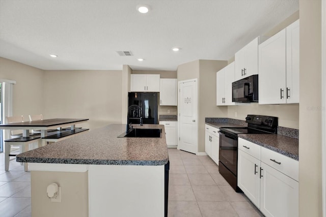 5067 Sable Chime Dr, Wimauma, FL 33598 - kitchen with black appliances, a sink, dark countertops, a kitchen island with sink, and recessed lighting