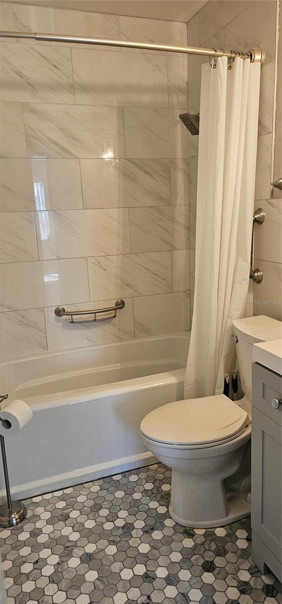 full bathroom featuring toilet, shower / bath combo with shower curtain, and vanity