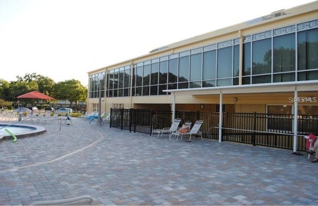 view of property's community with a pool, fence, and a patio