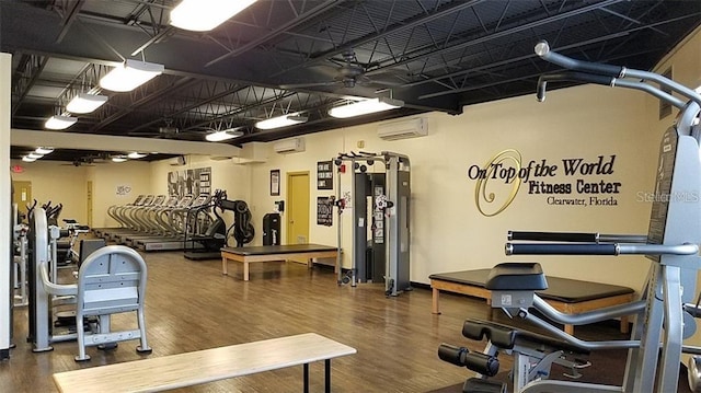 gym with wood finished floors and an AC wall unit