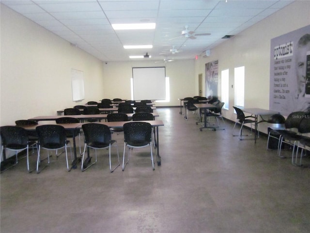 misc room featuring plenty of natural light, a drop ceiling, finished concrete flooring, and a ceiling fan