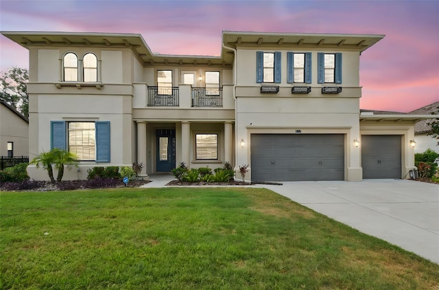 view of front facade with a balcony, stucco siding, driveway, and a yard