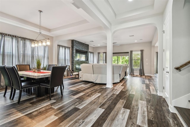 dining room with a raised ceiling, dark wood finished floors, and arched walkways