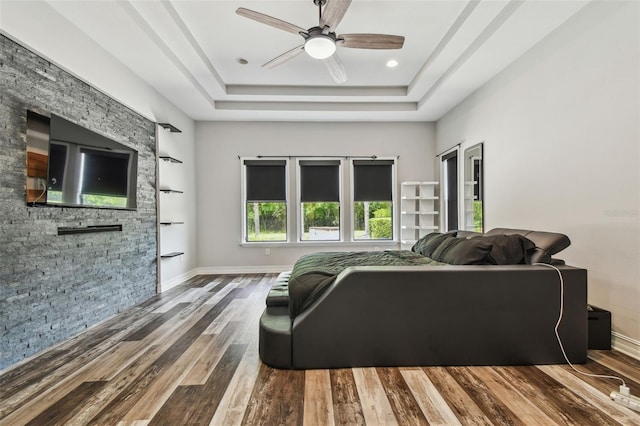 living room with a raised ceiling, a ceiling fan, wood finished floors, and baseboards