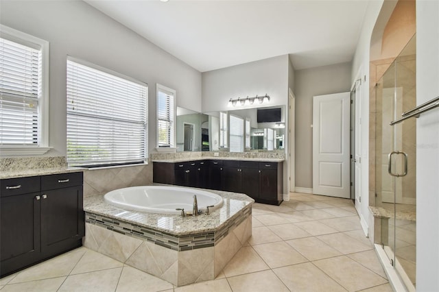 bathroom with a bath, a shower stall, tile patterned flooring, and vanity