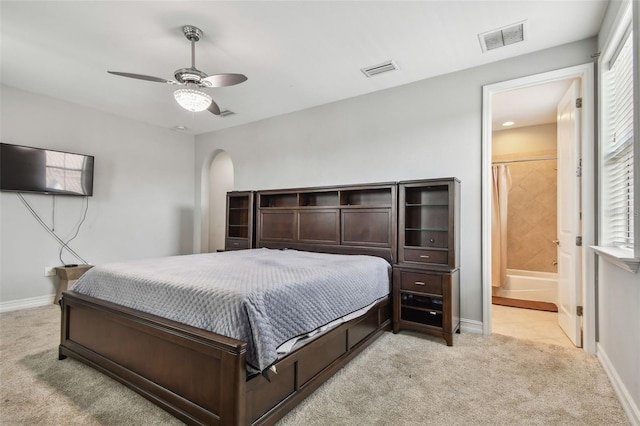 bedroom with light carpet, baseboards, connected bathroom, and a ceiling fan