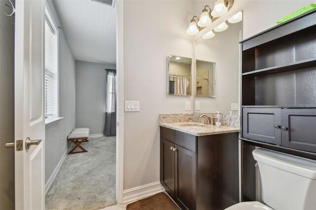 bathroom with toilet, vanity, and baseboards