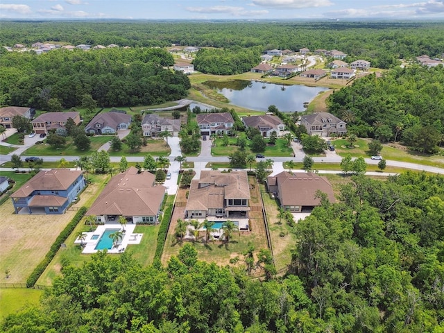 aerial perspective of suburban area with a large body of water, a heavily wooded area, and a pool