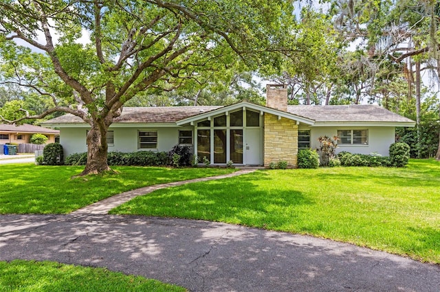 1675 Robin Hood Ln, Clearwater, FL 33764 - view of front of home featuring a chimney, a front yard, stucco siding, and a sunroom