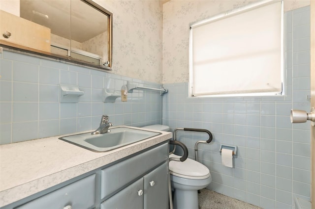 1675 Robin Hood Ln, Clearwater, FL 33764 - bathroom with vanity, toilet, wallpapered walls, wainscoting, and tile walls