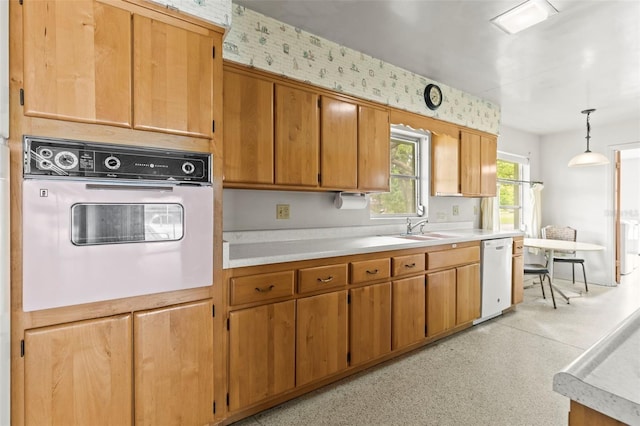 1675 Robin Hood Ln, Clearwater, FL 33764 - kitchen with white appliances, light countertops, a sink, decorative light fixtures, and brown cabinets