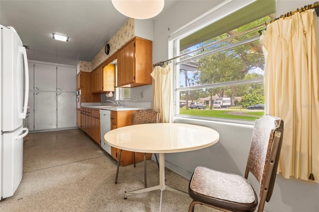 1675 Robin Hood Ln, Clearwater, FL 33764 - kitchen with white appliances, light countertops, brown cabinetry, and a sink