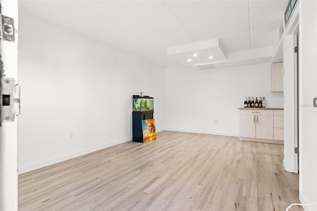 empty room with light wood-style flooring, a dry bar, recessed lighting, and baseboards