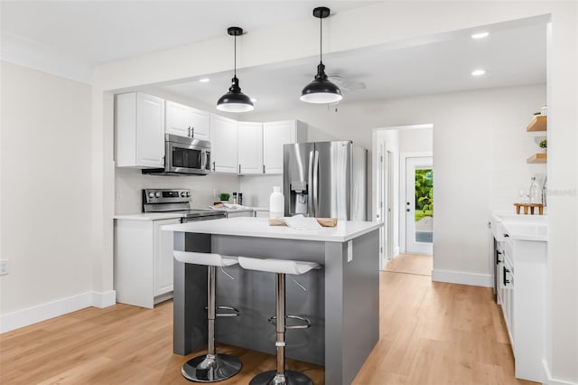 526 62nd Ave NE, Saint Petersburg, FL 33702 - kitchen featuring appliances with stainless steel finishes, light wood-style flooring, a breakfast bar area, white cabinets, and light countertops
