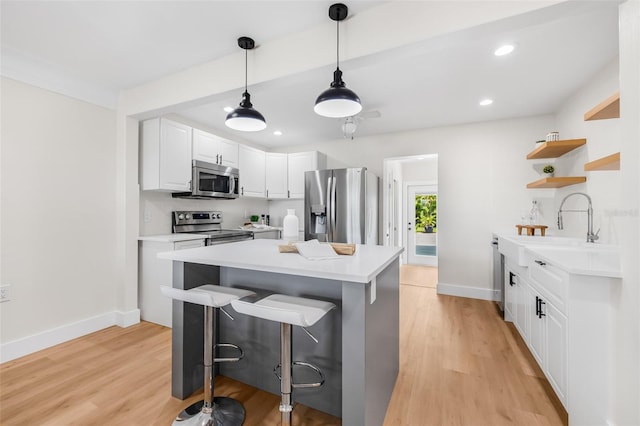 526 62nd Ave NE, Saint Petersburg, FL 33702 - kitchen with appliances with stainless steel finishes, open shelves, light wood finished floors, light countertops, and a breakfast bar