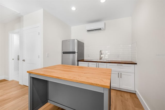 526 62nd Ave NE, Saint Petersburg, FL 33702 - kitchen featuring butcher block countertops, freestanding refrigerator, a sink, a wall unit AC, and white cabinets
