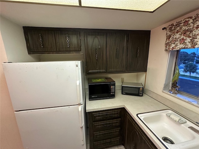 1200 37th St N Unit 403, Saint Petersburg, FL 33713 - kitchen with freestanding refrigerator, black microwave, a sink, light countertops, and dark brown cabinets