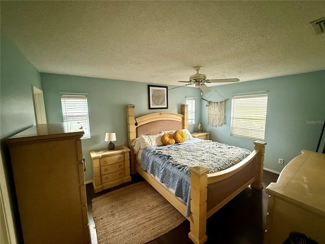 bedroom with a textured ceiling, multiple windows, baseboards, a ceiling fan, and wood finished floors