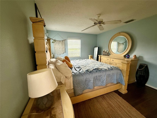 bedroom featuring dark wood finished floors, baseboards, ceiling fan, and a textured ceiling