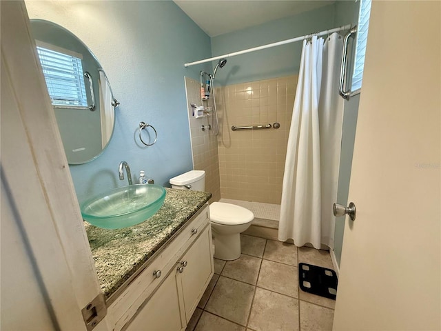 bathroom featuring toilet, vanity, a stall shower, and tile patterned floors