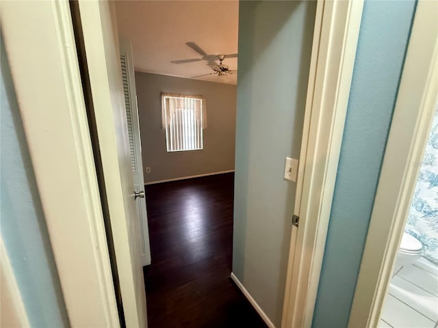 hallway featuring dark wood-style flooring and baseboards