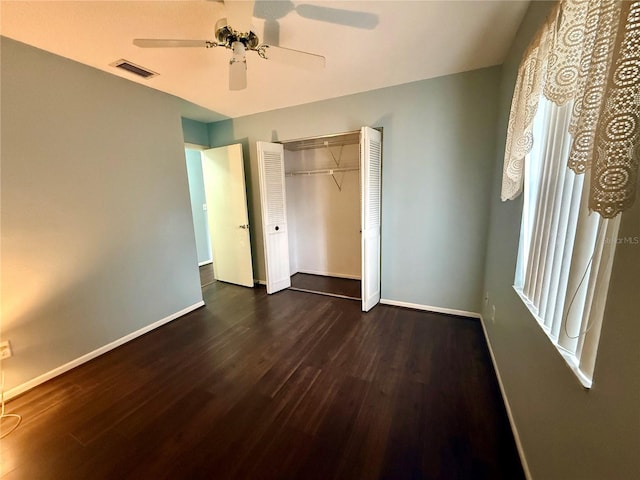 unfurnished bedroom featuring dark wood finished floors, baseboards, and a closet