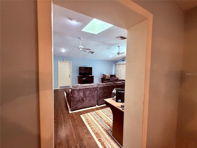hall featuring wood finished floors, a skylight, and vaulted ceiling