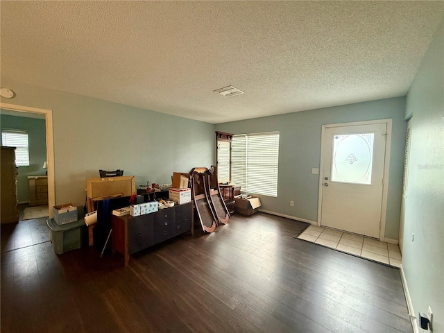 entrance foyer featuring hardwood / wood-style flooring, healthy amount of natural light, a textured ceiling, and baseboards