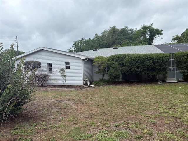 rear view of house with a lawn and roof with shingles