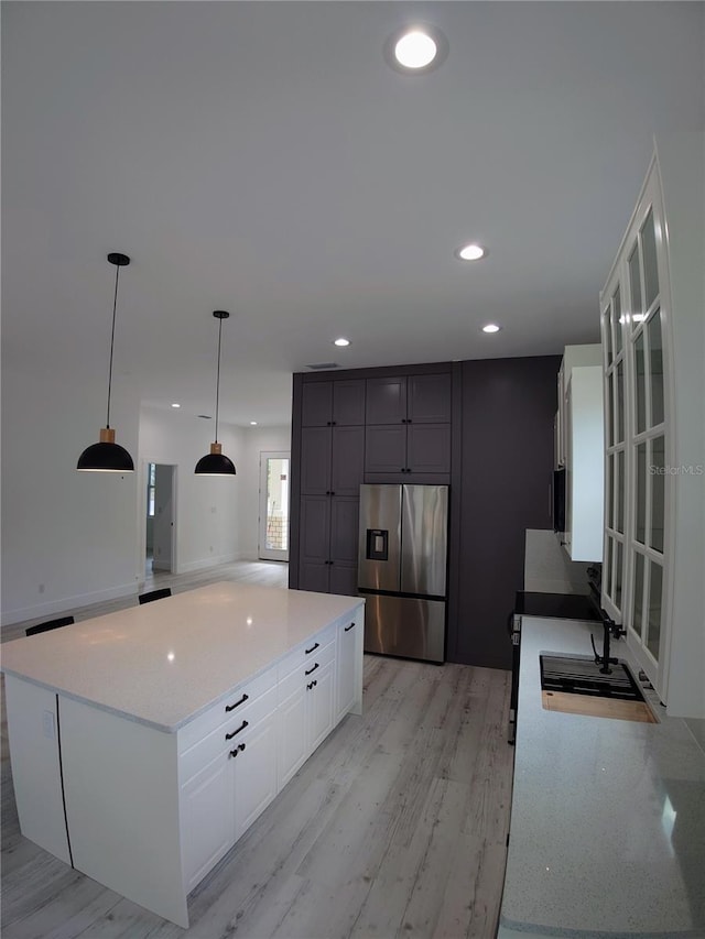 7013 N 15th St, Tampa, FL 33610 - kitchen with stainless steel fridge, white cabinets, a spacious island, light wood-type flooring, and pendant lighting