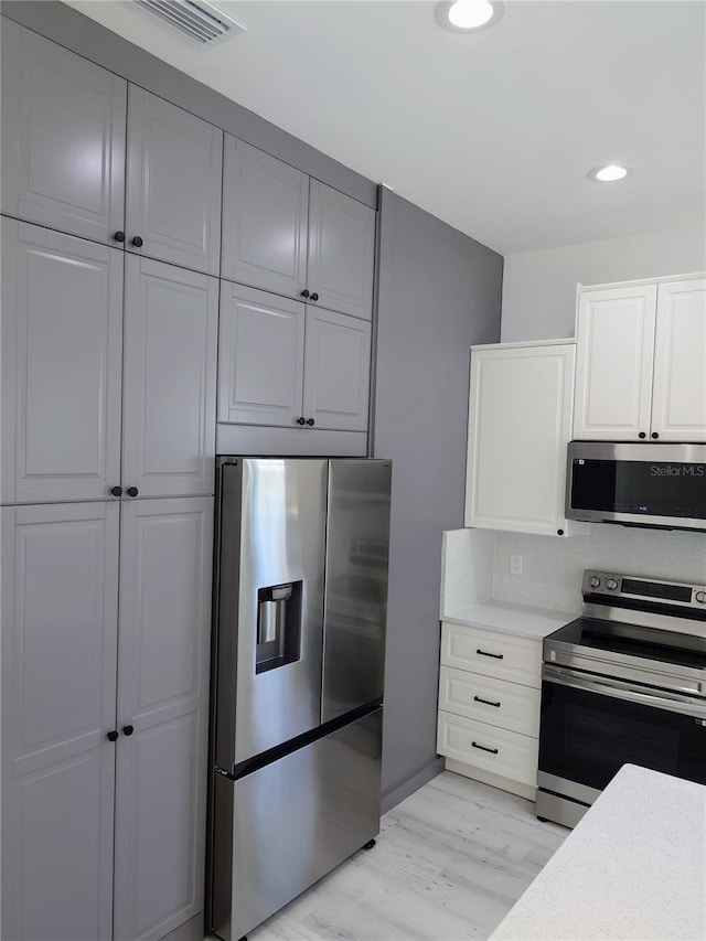 7013 N 15th St, Tampa, FL 33610 - kitchen featuring appliances with stainless steel finishes, light countertops, light wood-type flooring, recessed lighting, and white cabinetry