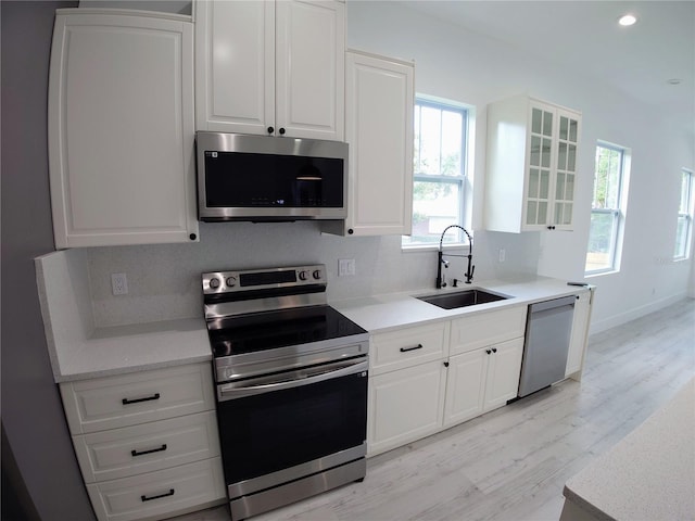7013 N 15th St, Tampa, FL 33610 - kitchen with appliances with stainless steel finishes, a sink, light wood-style floors, white cabinetry, and recessed lighting