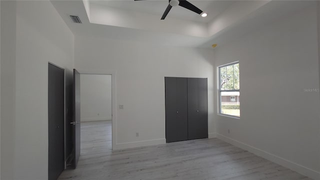 7013 N 15th St, Tampa, FL 33610 - unfurnished bedroom featuring a raised ceiling, light wood finished floors, baseboards, a closet, and a ceiling fan
