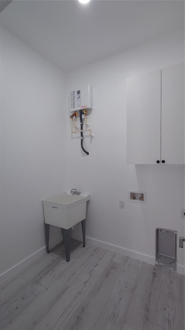 7013 N 15th St, Tampa, FL 33610 - laundry room with wood finished floors, washer hookup, baseboards, and tankless water heater