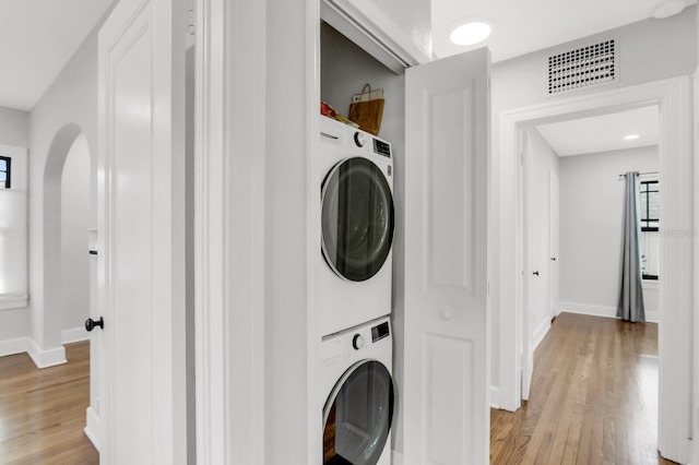 2859 Dartmouth Ave N, Saint Petersburg, FL 33713 - laundry area featuring stacked washer and clothes dryer, arched walkways, light wood-style floors, baseboards, and plenty of natural light