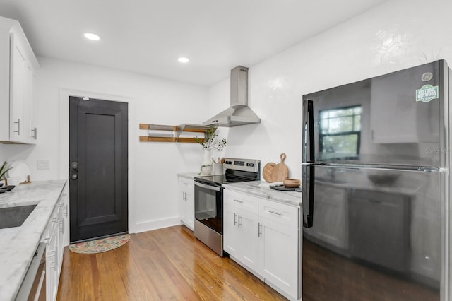2859 Dartmouth Ave N, Saint Petersburg, FL 33713 - kitchen featuring stainless steel range with electric cooktop, freestanding refrigerator, wall chimney exhaust hood, light wood-style floors, and white cabinetry