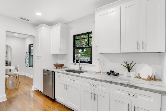 2859 Dartmouth Ave N, Saint Petersburg, FL 33713 - kitchen with dishwasher, a sink, white cabinets, light wood-type flooring, and light stone counters