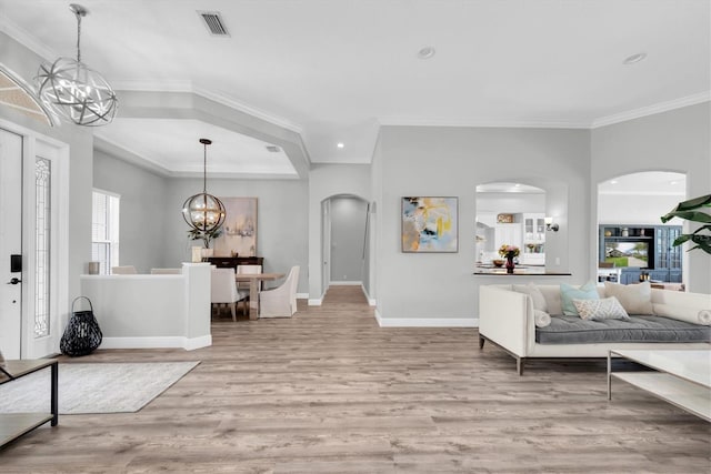 entryway featuring arched walkways, a chandelier, wood finished floors, recessed lighting, and ornamental molding