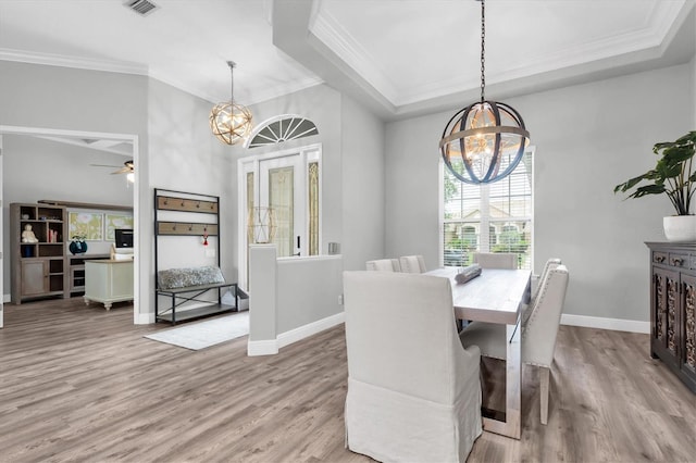 dining room featuring a chandelier, wood finished floors, ornamental molding, baseboards, and a raised ceiling