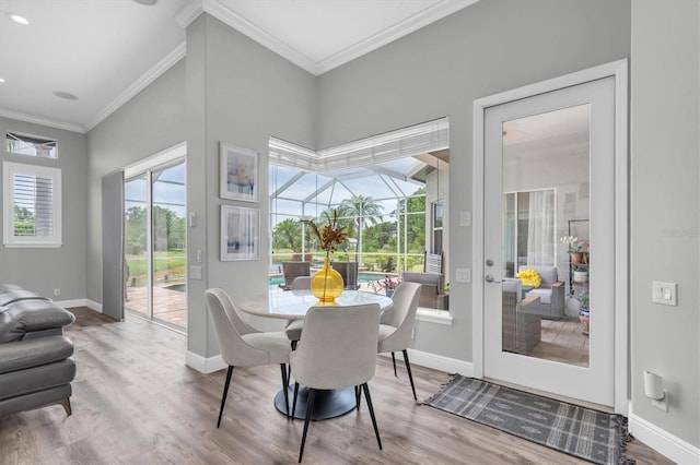 dining room featuring wood finished floors, crown molding, and baseboards