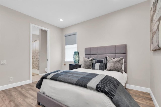 bedroom with baseboards, recessed lighting, wood finished floors, and ensuite bathroom